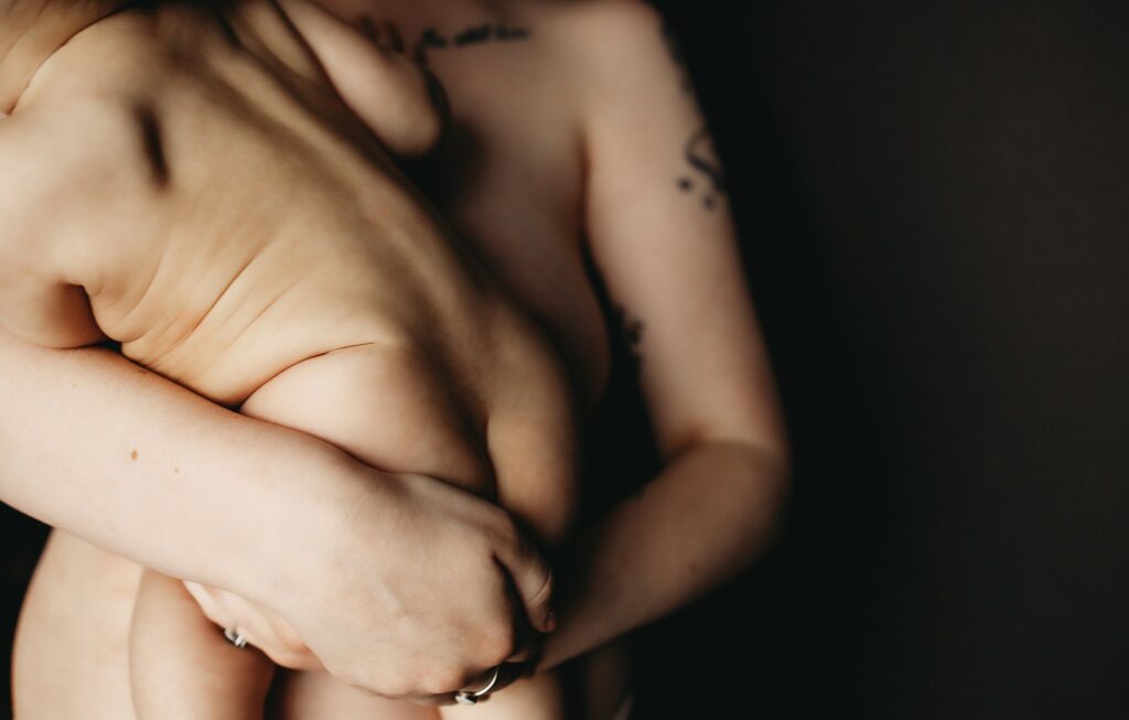 A mother holding her child, skin to skin, to showcase connection and motherhood through use of boudoir photography and nudity