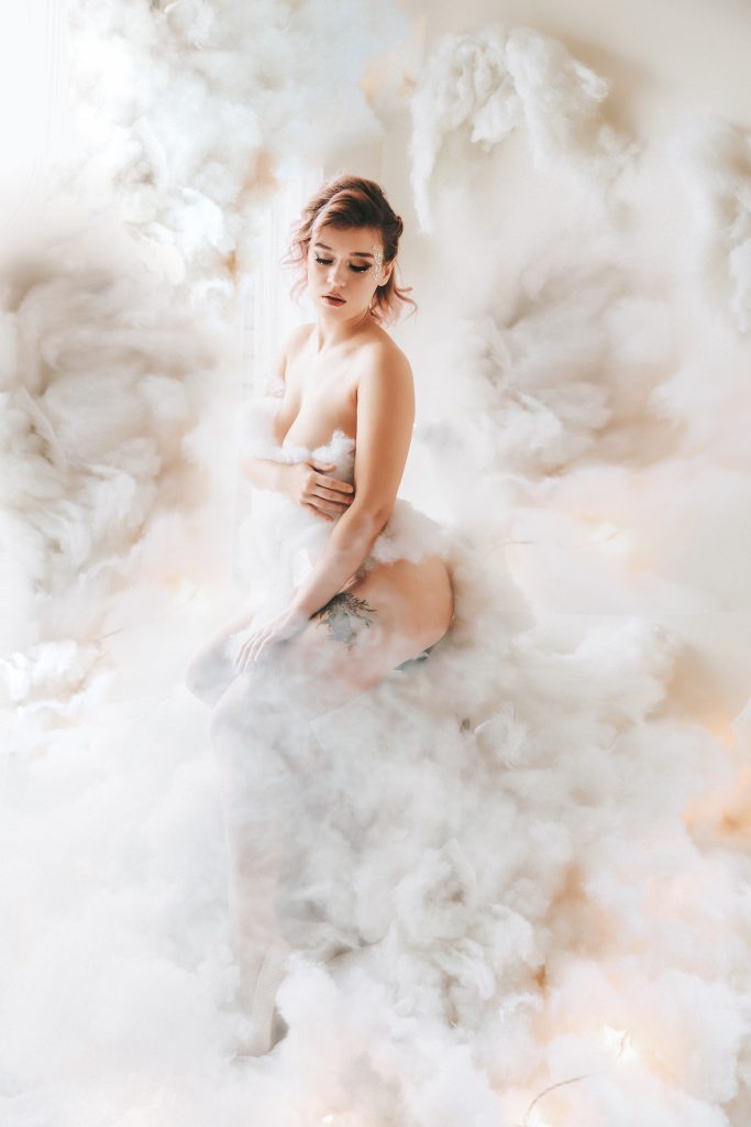 beautiful woman looking on the side sitting on light bright and airy clouds nude holding breasts and thigh Dijana Szewczyk photography Portland Oregon Boudoir Washington