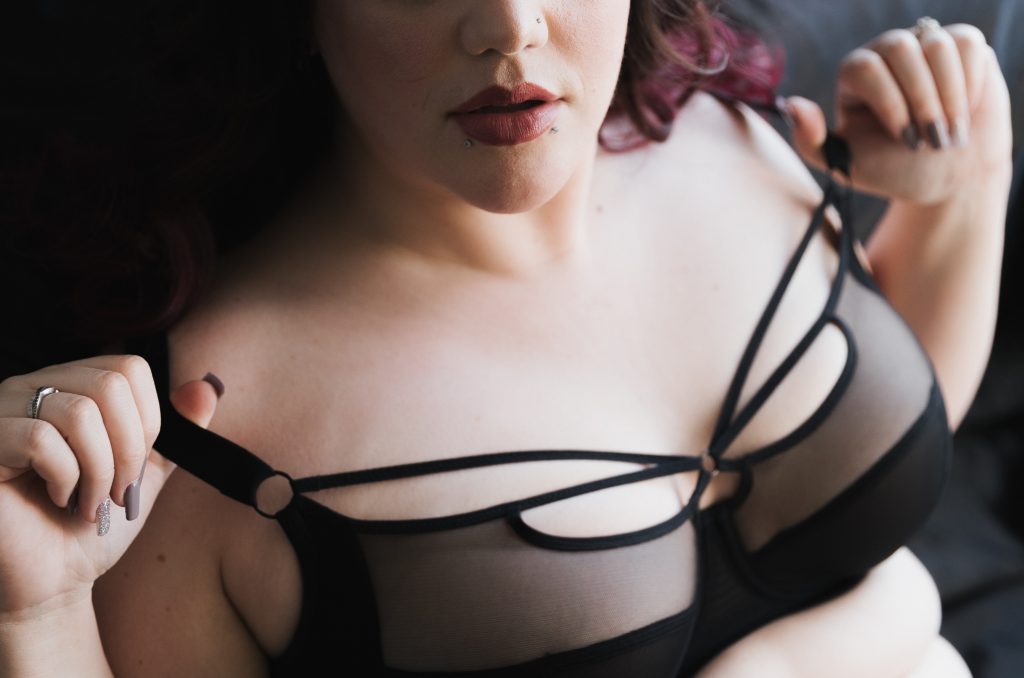 white woman with snakebite piercing and dark peach lip stick in black lingerie pulling bra straps off should burgundy hair pale skin Dijana Szewczyk photography Portland Oregon Boudoir Washington