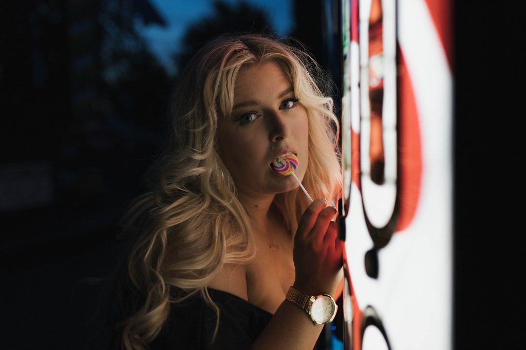 blonde sucking lollipop at amusement park night